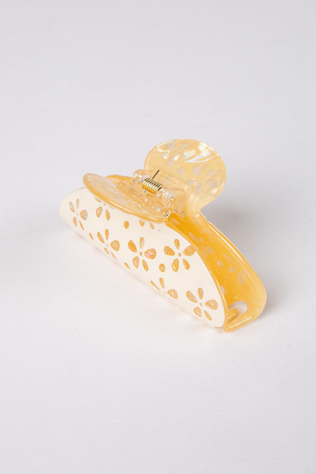 Yellow hair clip with gold accents on a light gray background