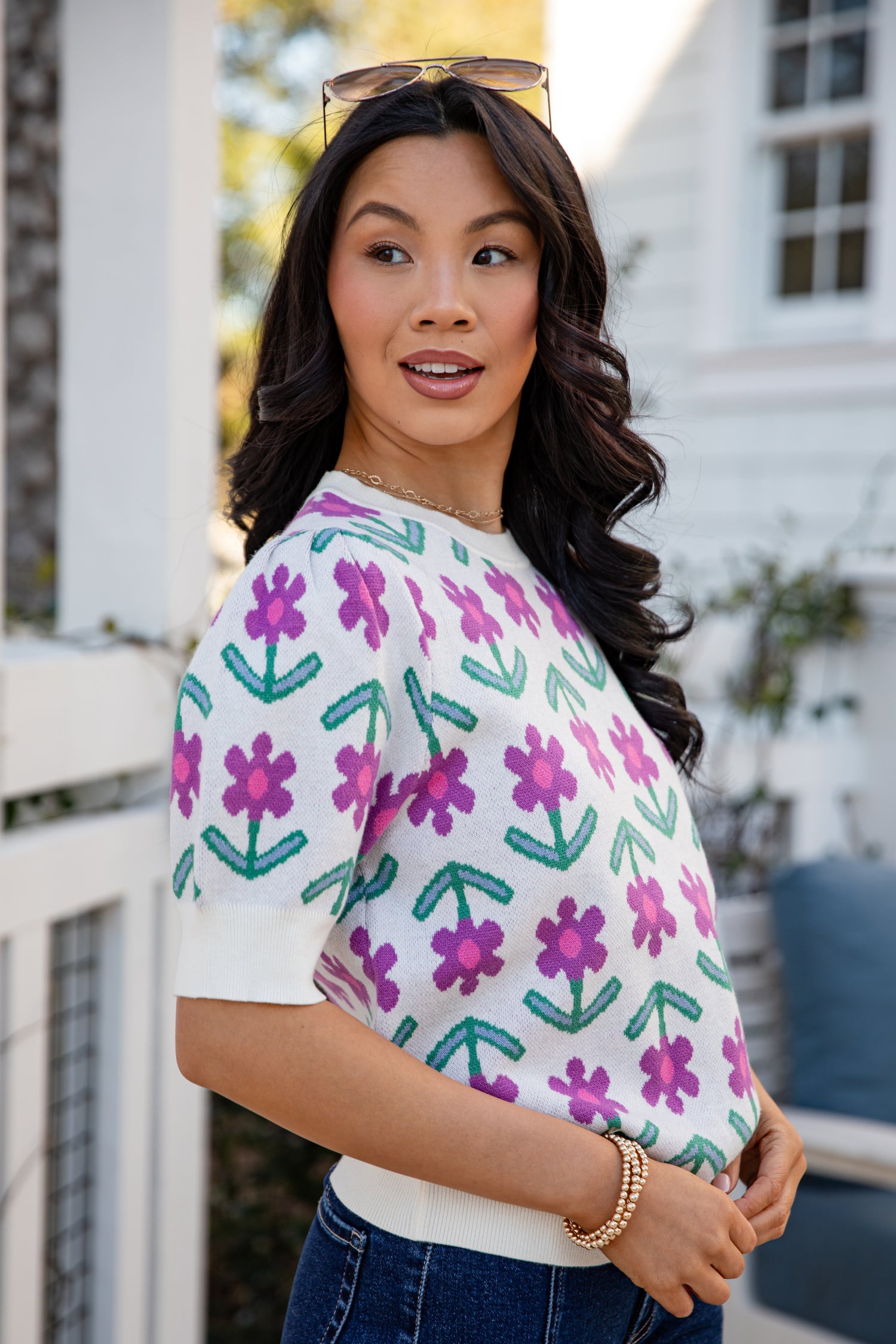 Woman wearing a white shirt with pink floral patterns outdoors.