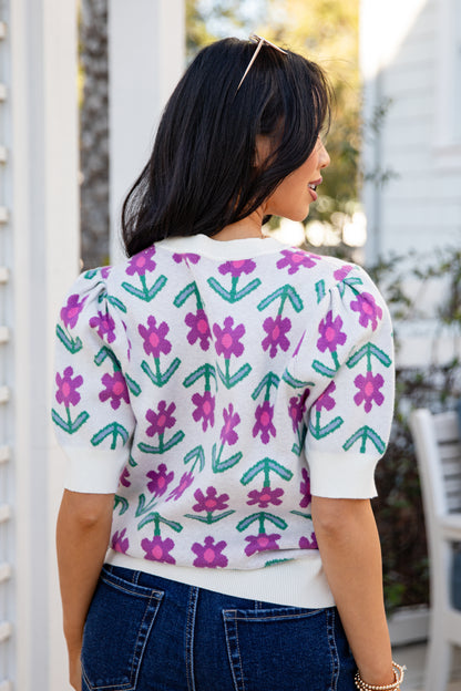 Person wearing a white shirt with purple floral patterns outdoors