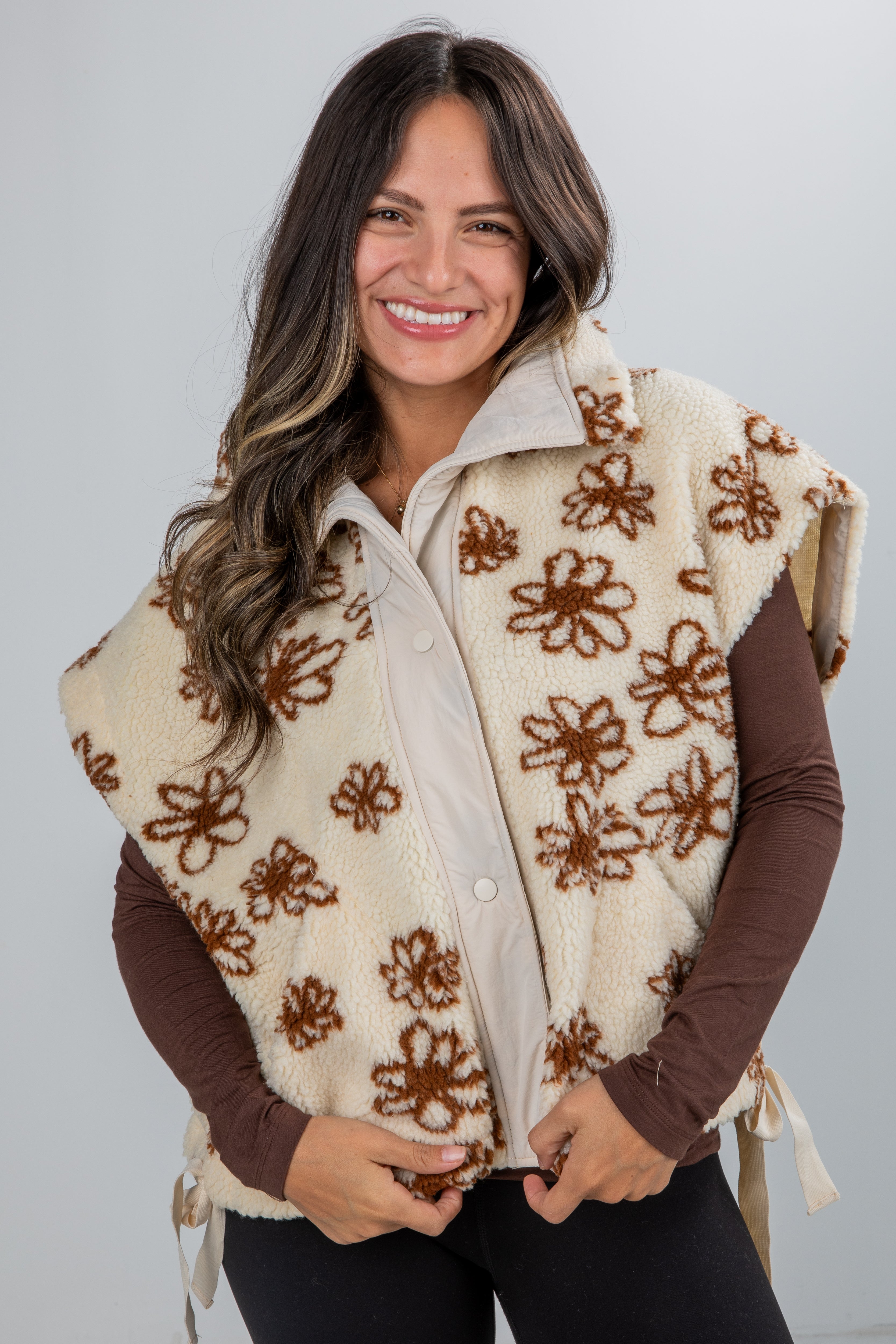 Woman wearing a patterned vest over a shirt with a plain background