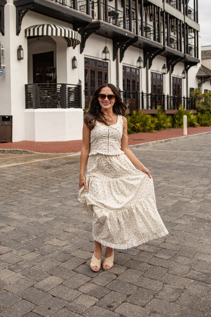 Woman in a white dress standing on a cobblestone street with a building in the background