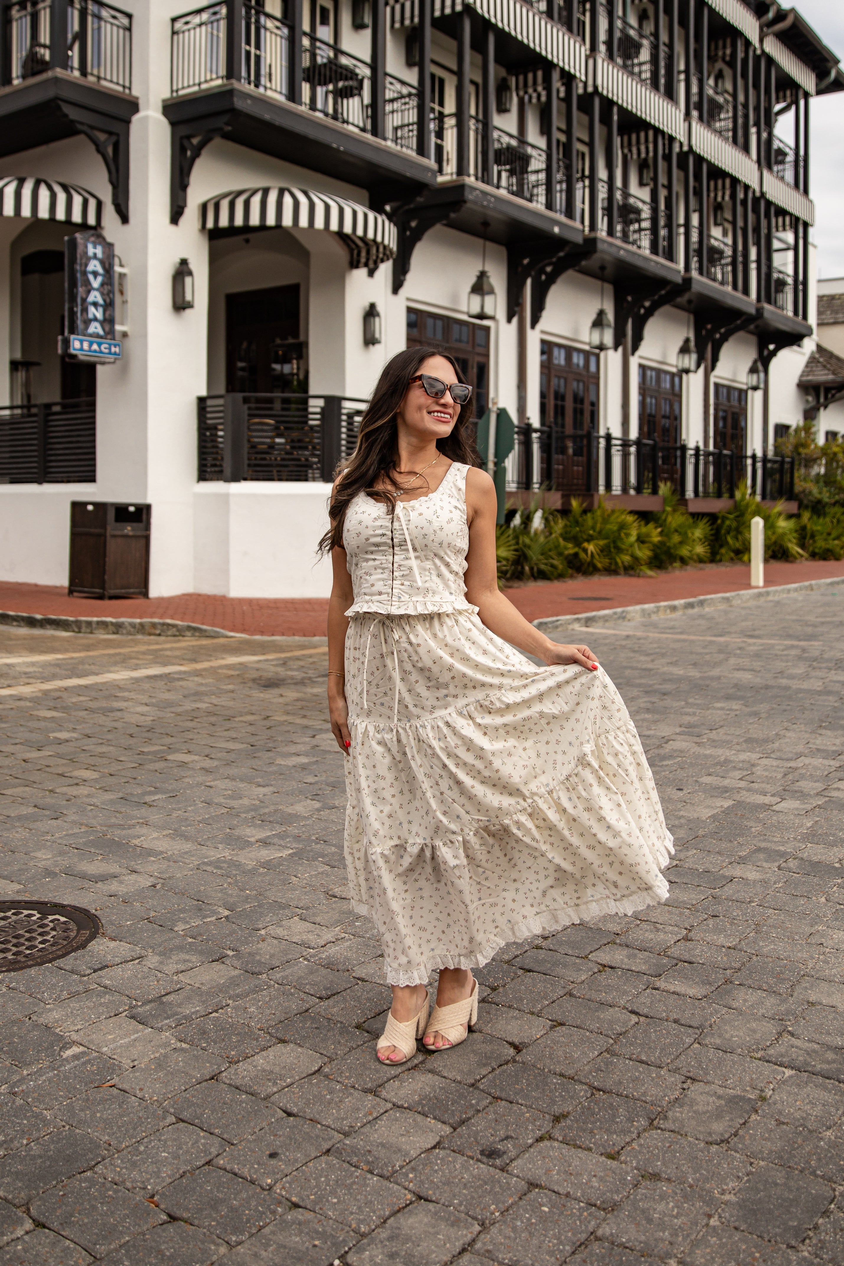 Woman in a white lace dress standing on a street with a building in the background