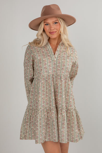 Woman wearing a patterned dress and brown hat on a plain background