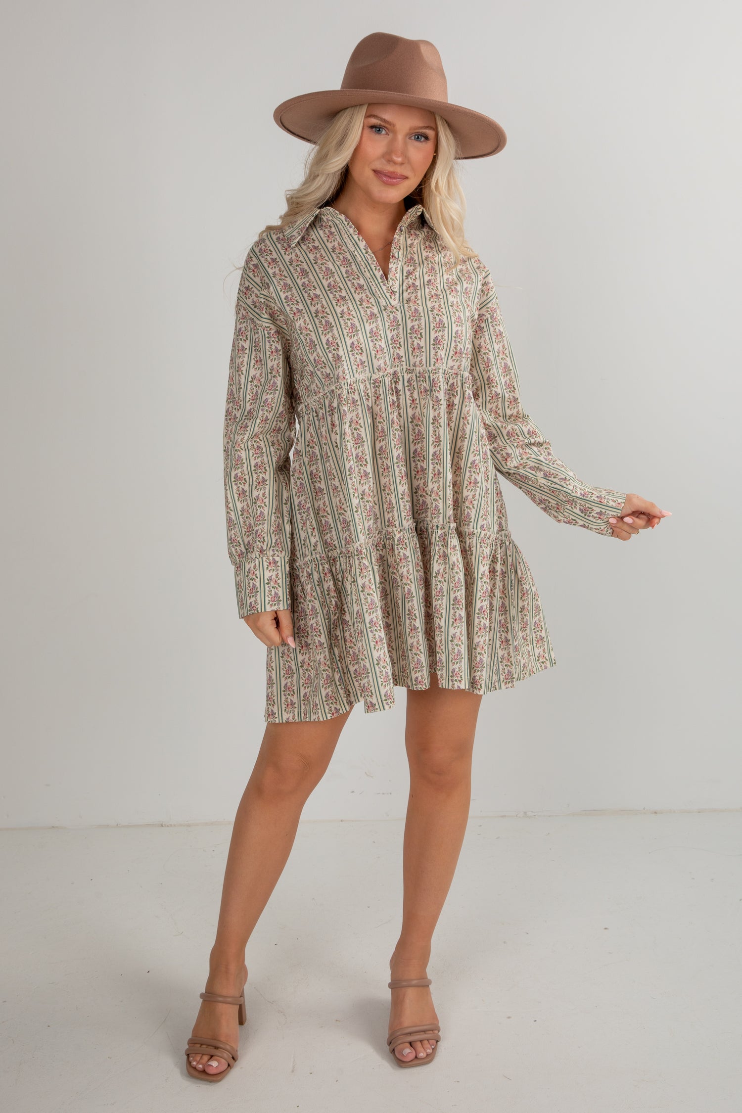 Woman wearing a patterned dress and brown hat on a white background