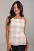 A woman wearing a beige and white gingham check sleeveless top, paired with black pants, standing against a light gray studio background.