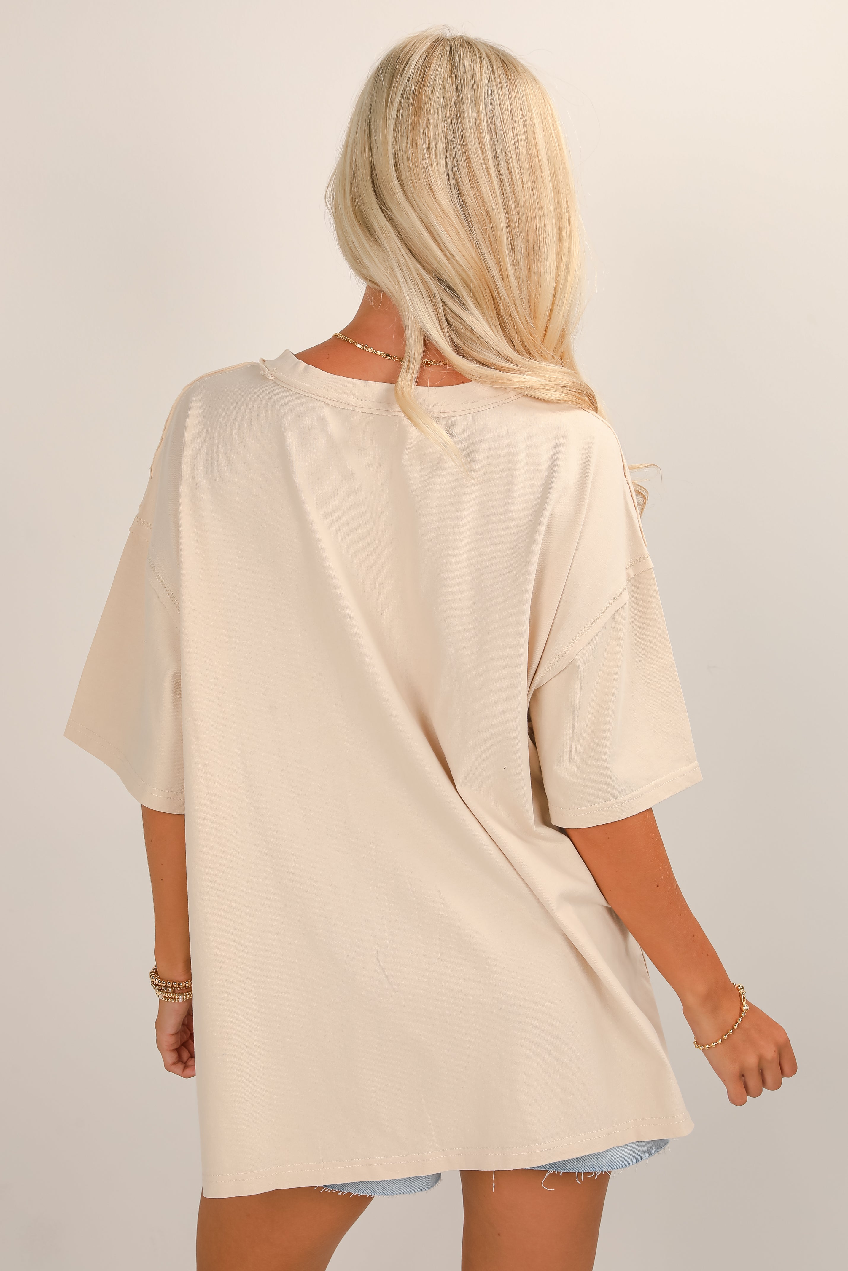 Woman wearing a beige oversized t-shirt on a plain background