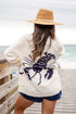 Person wearing a cream cardigan with a crab pattern by the ocean