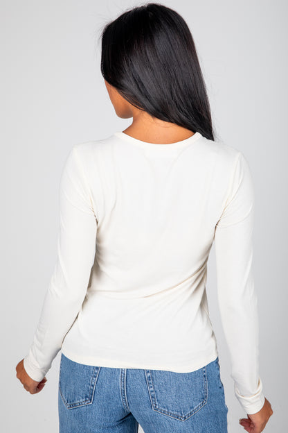 Person wearing a white long-sleeve top and blue jeans on a plain background