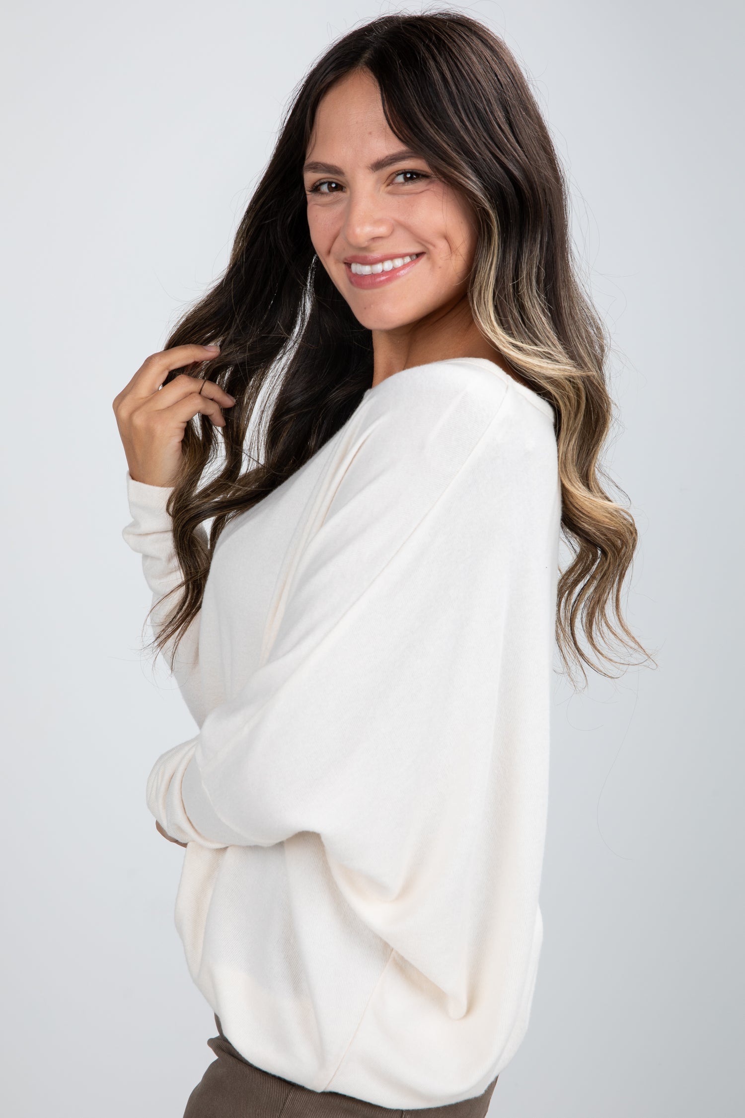Woman wearing a white sweater against a plain background