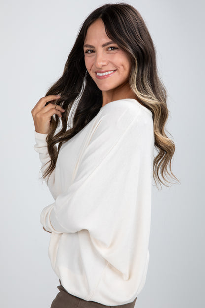 Woman wearing a white sweater against a plain background