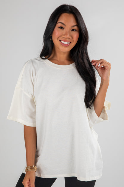 Woman wearing a white oversized t-shirt against a plain background