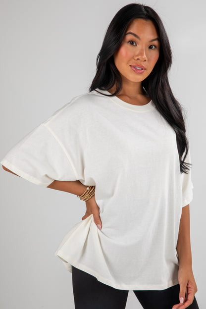 Woman wearing a white oversized t-shirt against a plain background