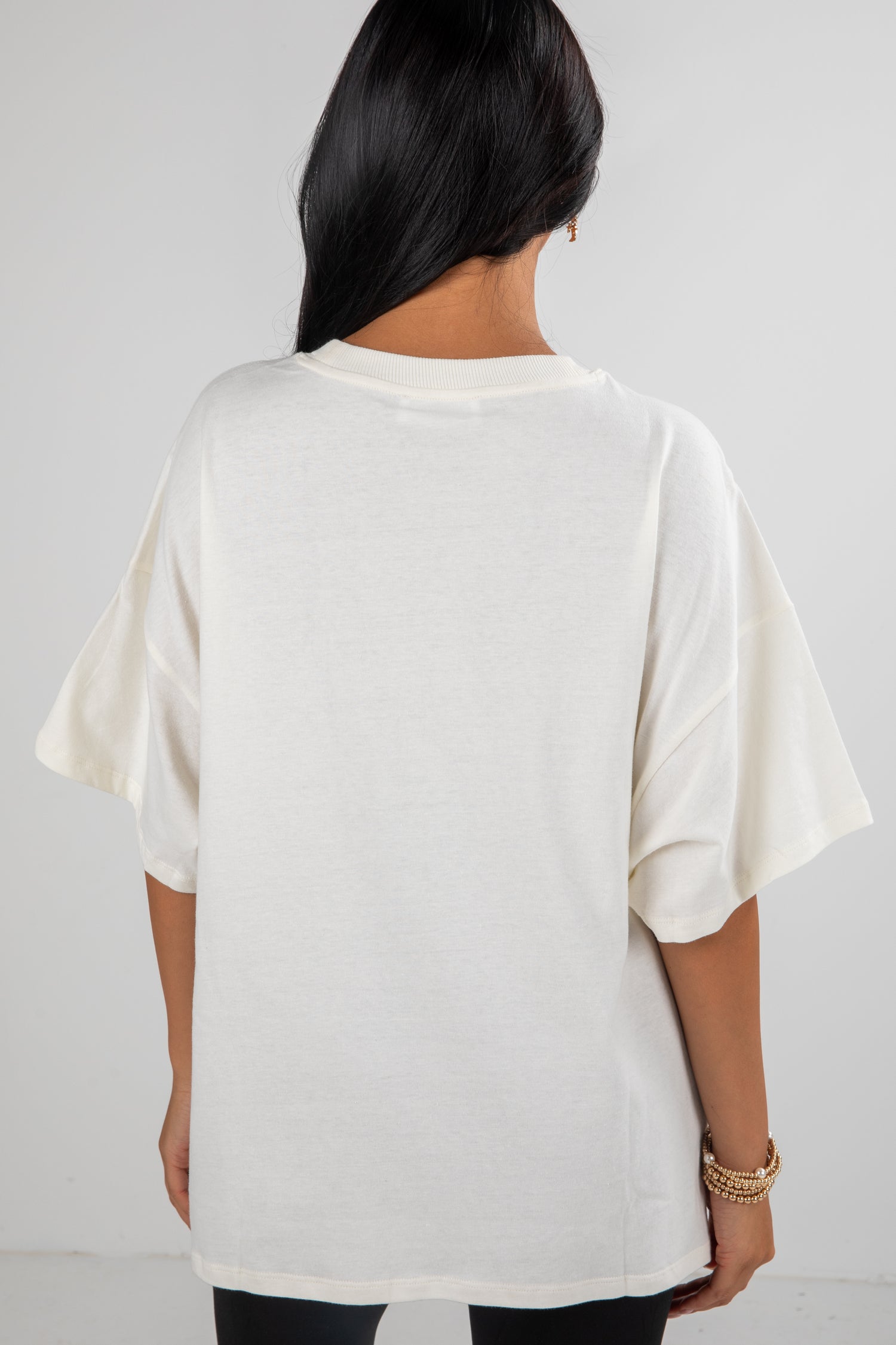 Person wearing a white oversized t-shirt on a plain background