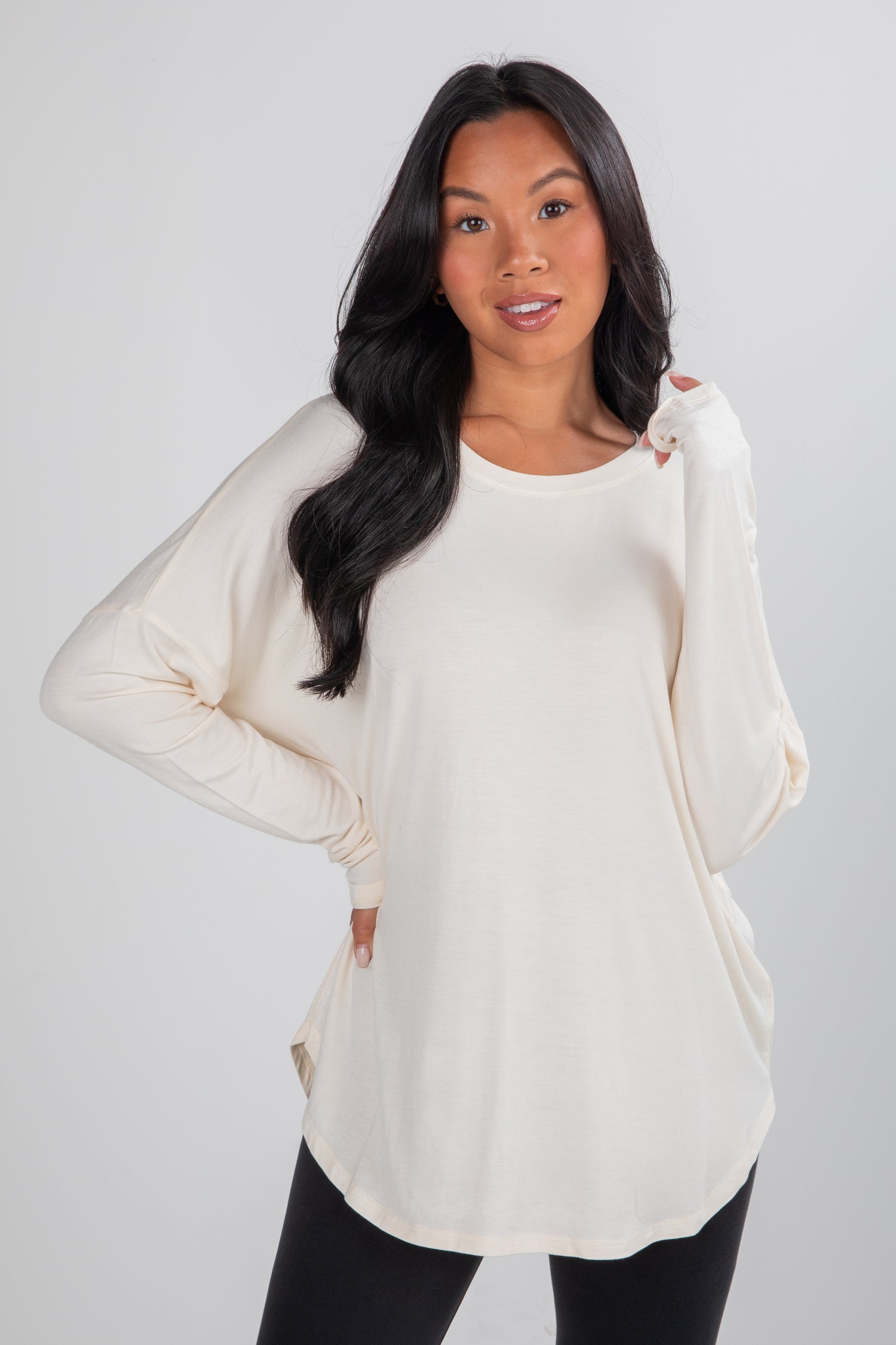 Woman wearing a cream-colored long-sleeve top against a plain background