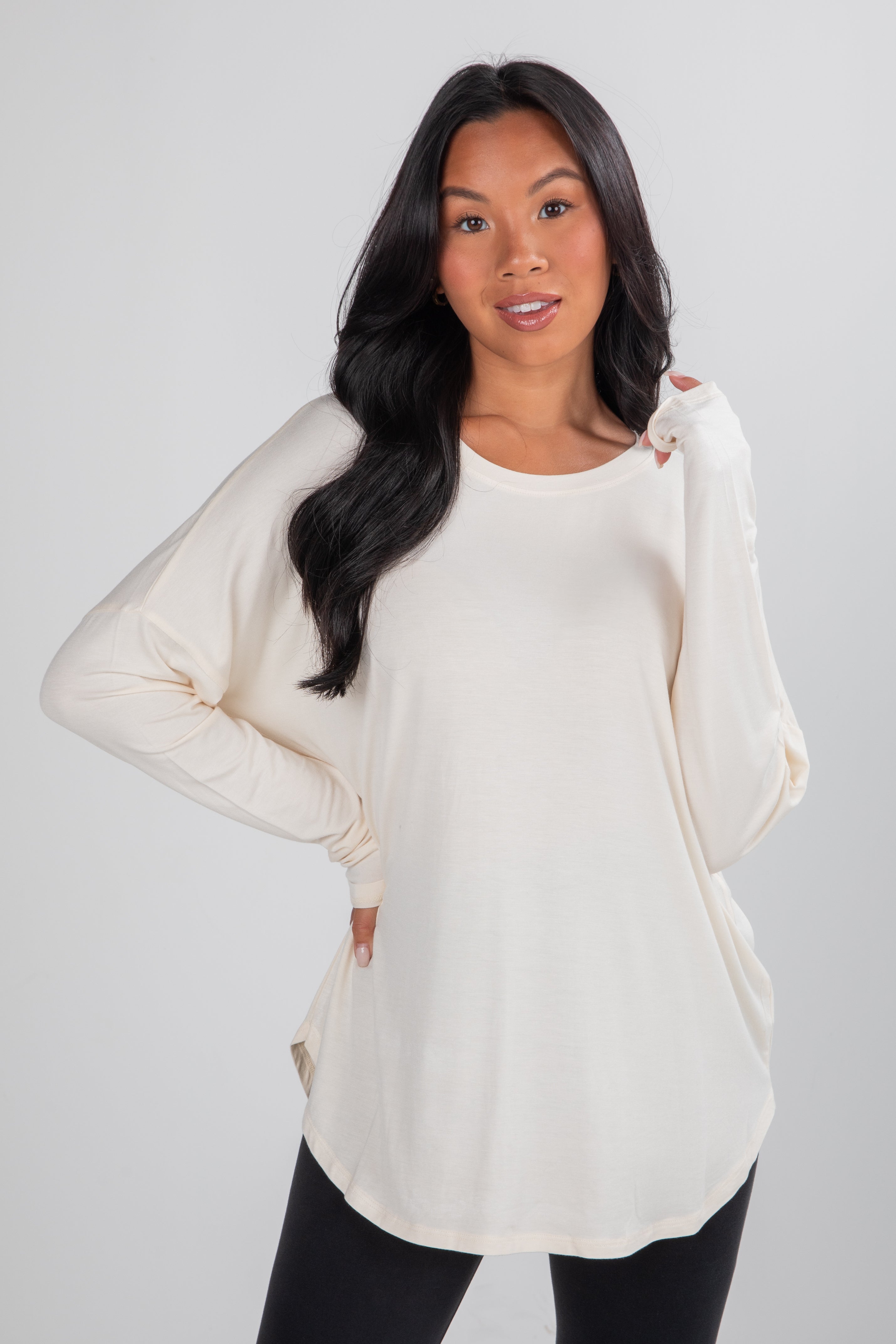 Woman wearing a cream-colored long-sleeve top against a plain background