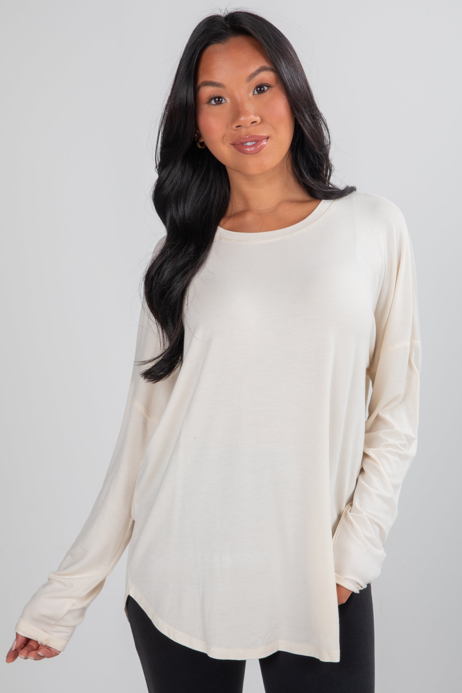 Woman wearing a beige long-sleeve top against a plain background