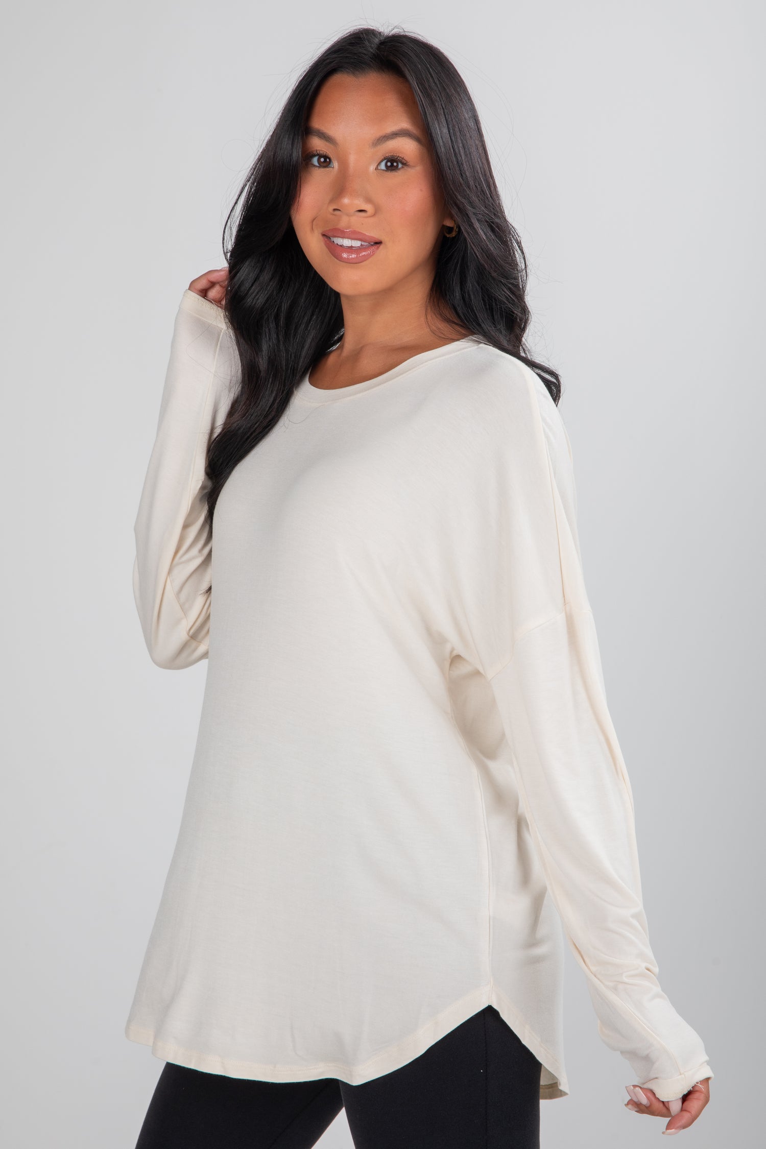 Woman wearing a cream long-sleeve top against a plain background