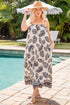 Woman in a leaf-patterned dress standing by a pool