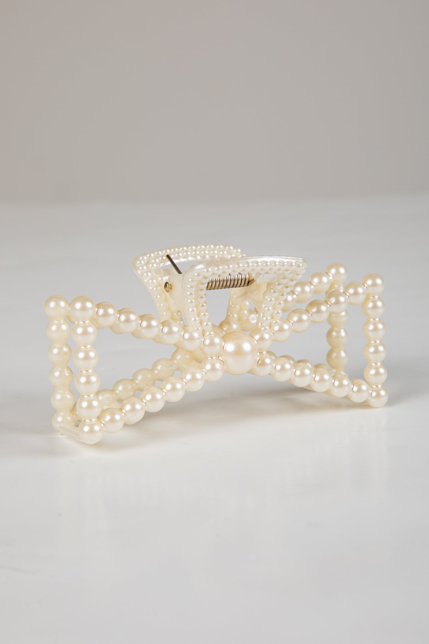 Pearl bow hair clip on a light gray background