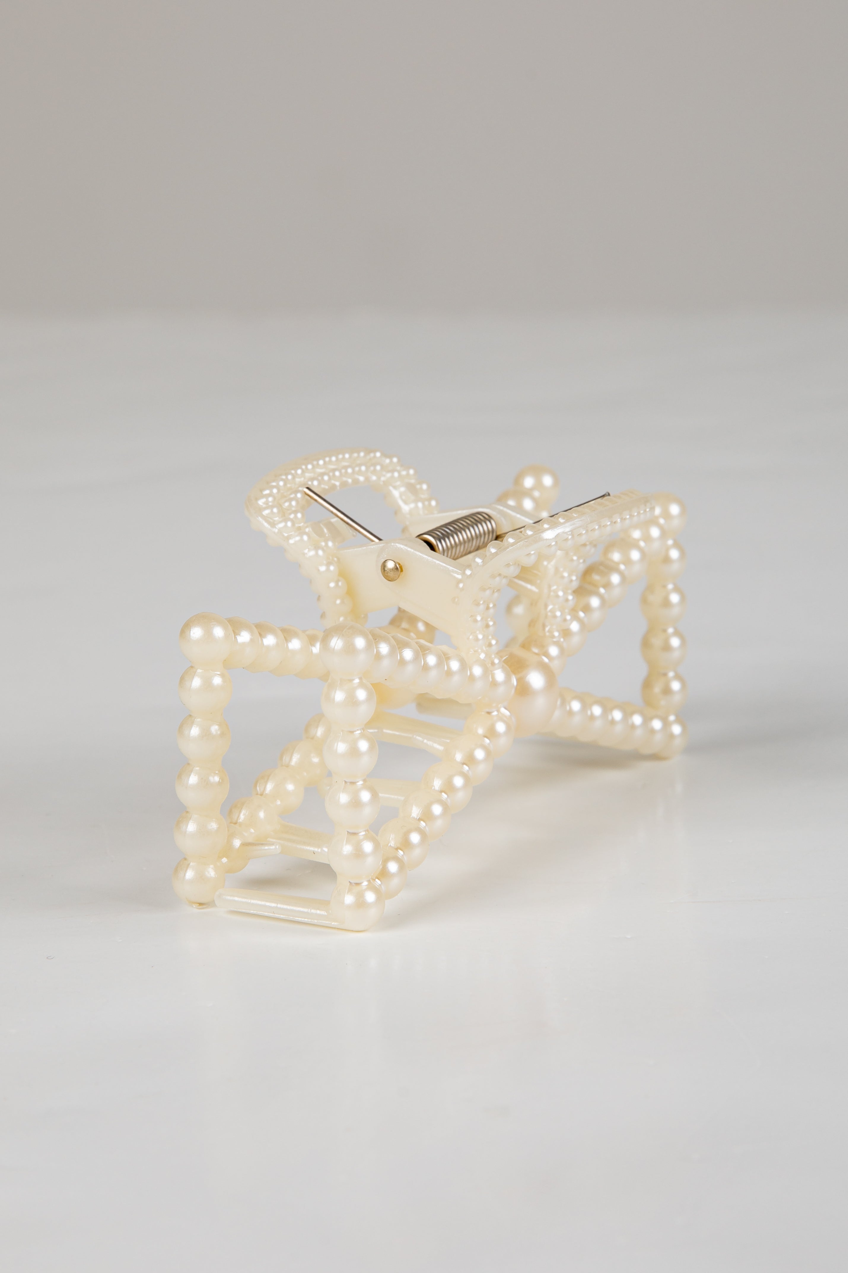 Pearl-clad clutch bag on a light gray background