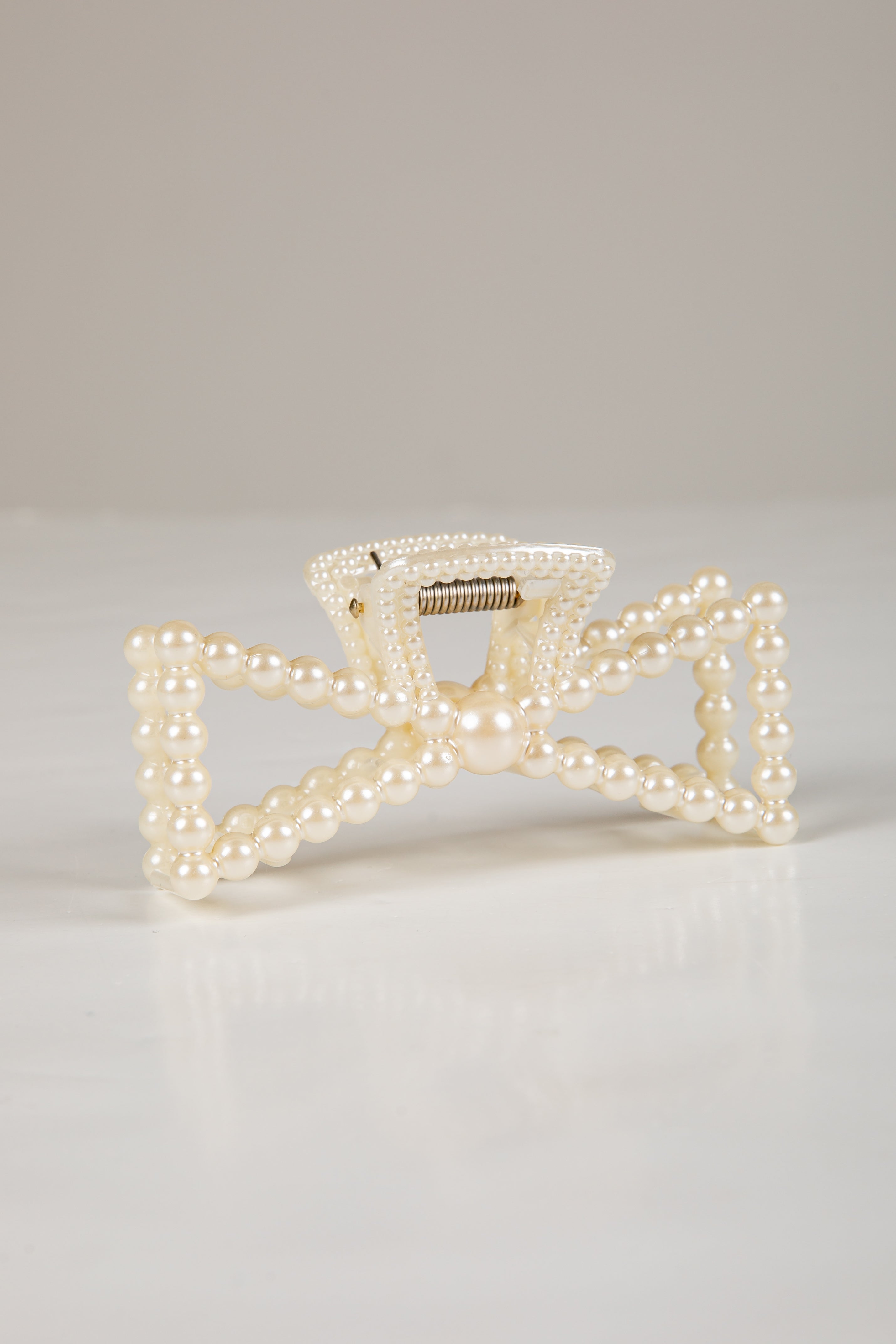 Pearl-handled clutch bag on a light gray background