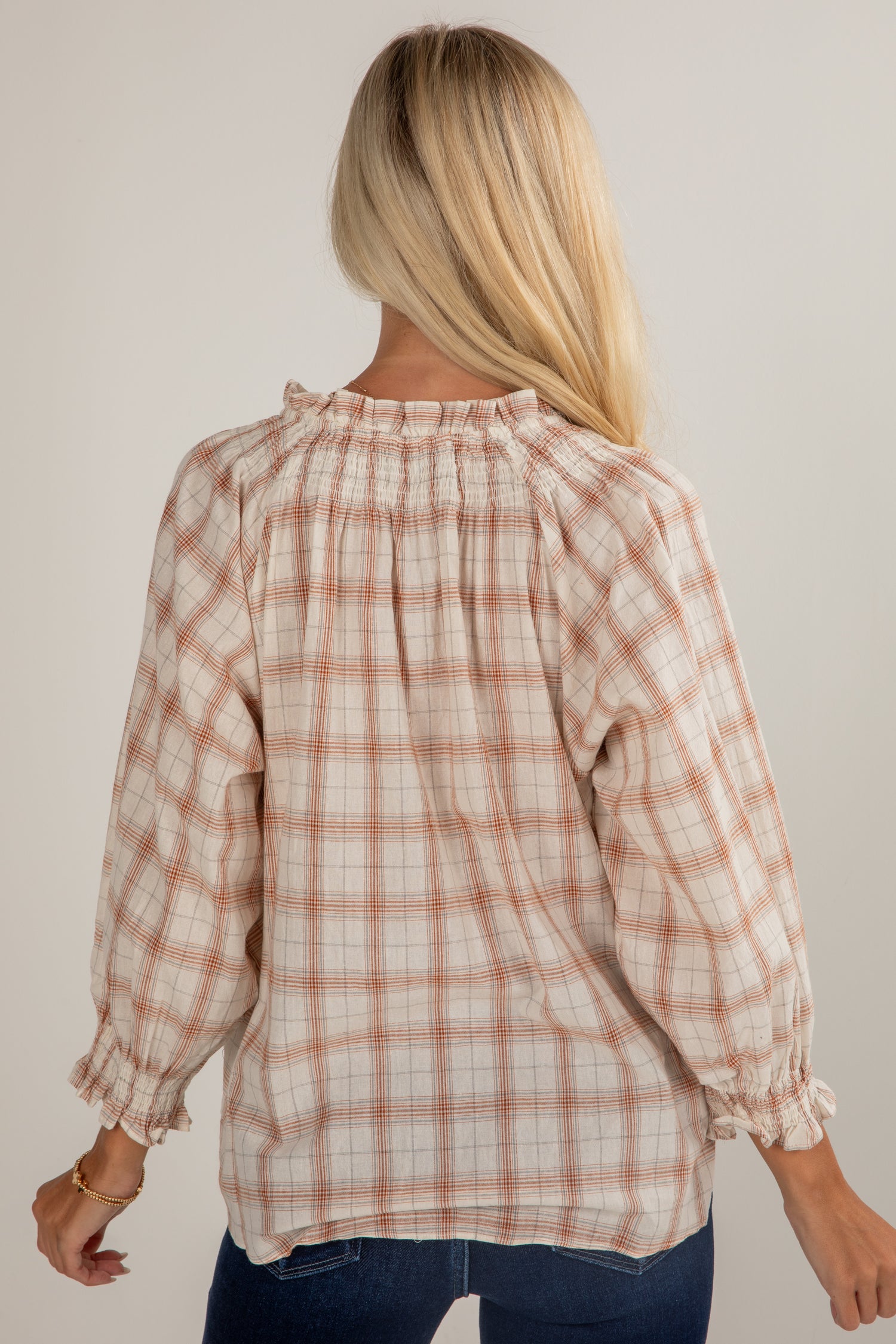 Person wearing a plaid blouse with long sleeves against a plain background