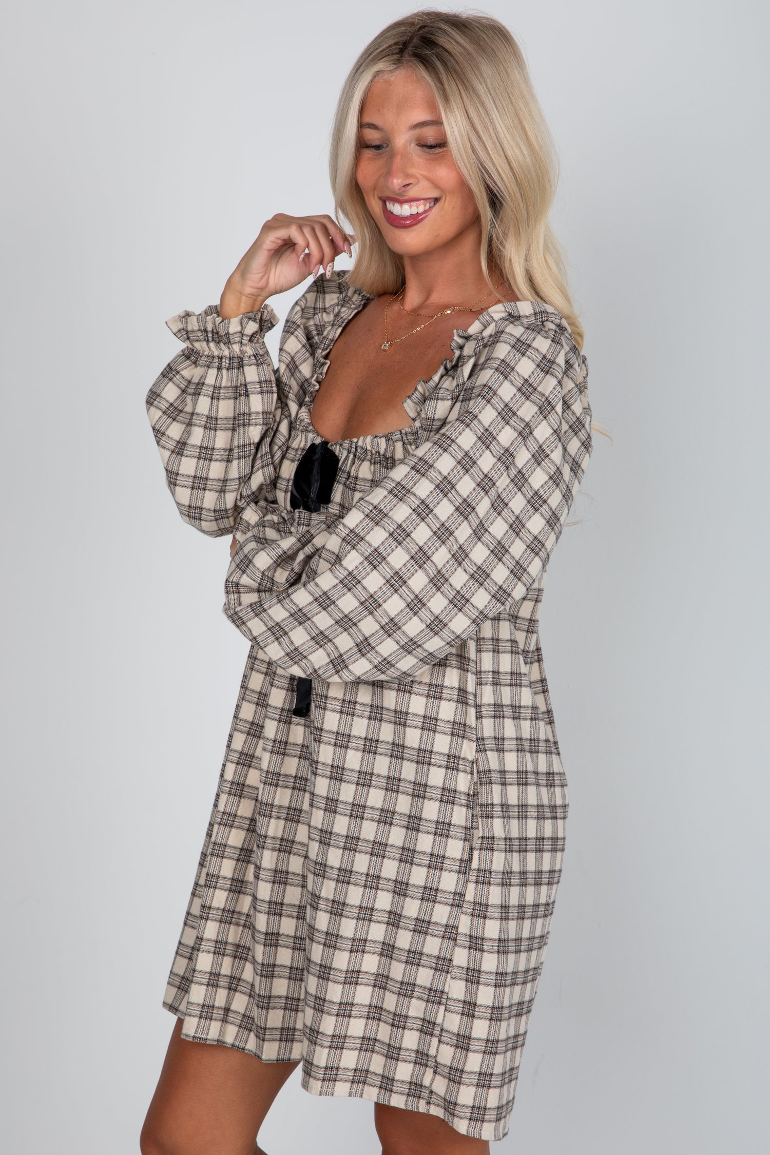 Woman wearing a plaid dress against a plain background