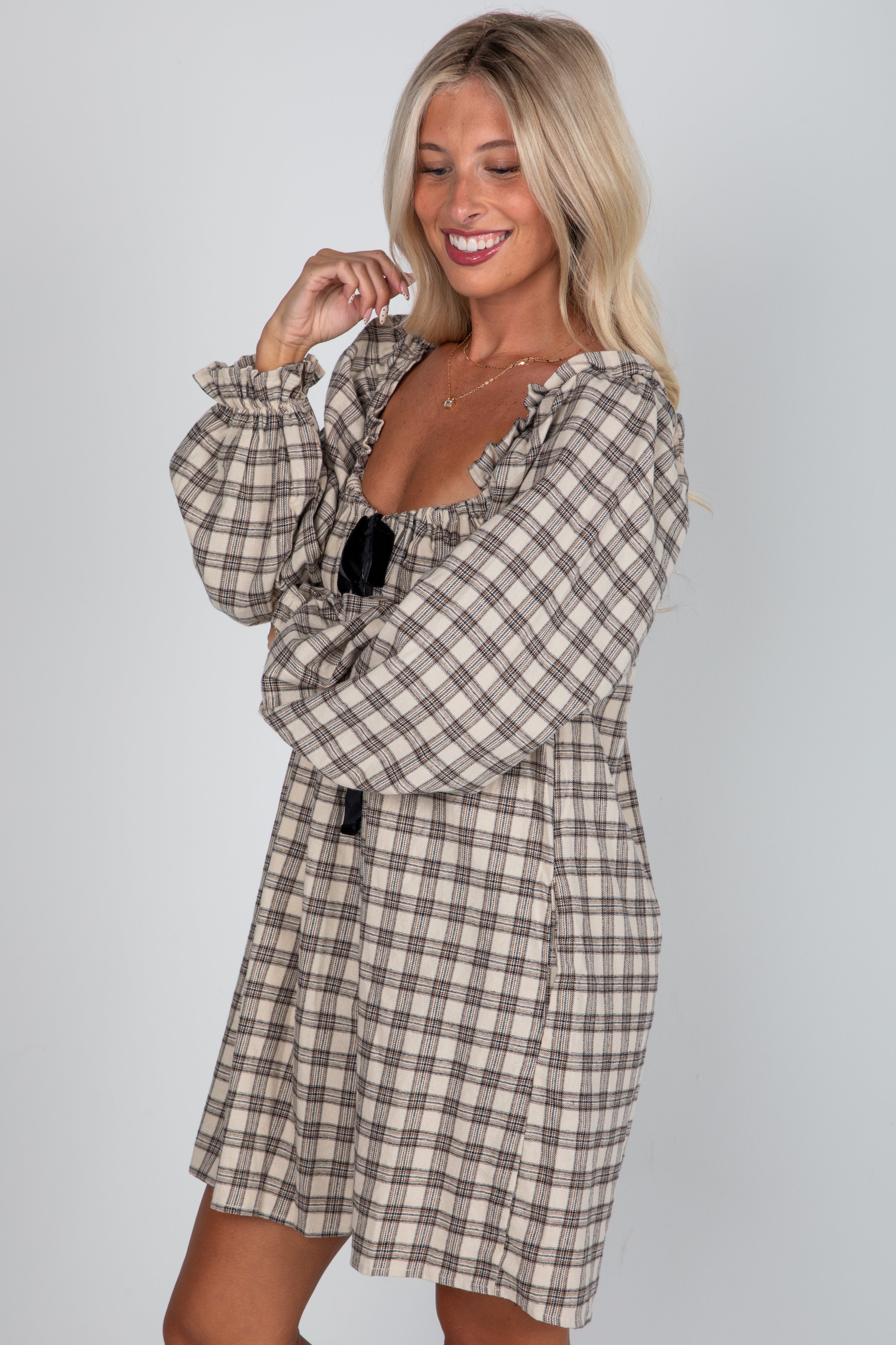 Woman wearing a plaid dress against a plain background