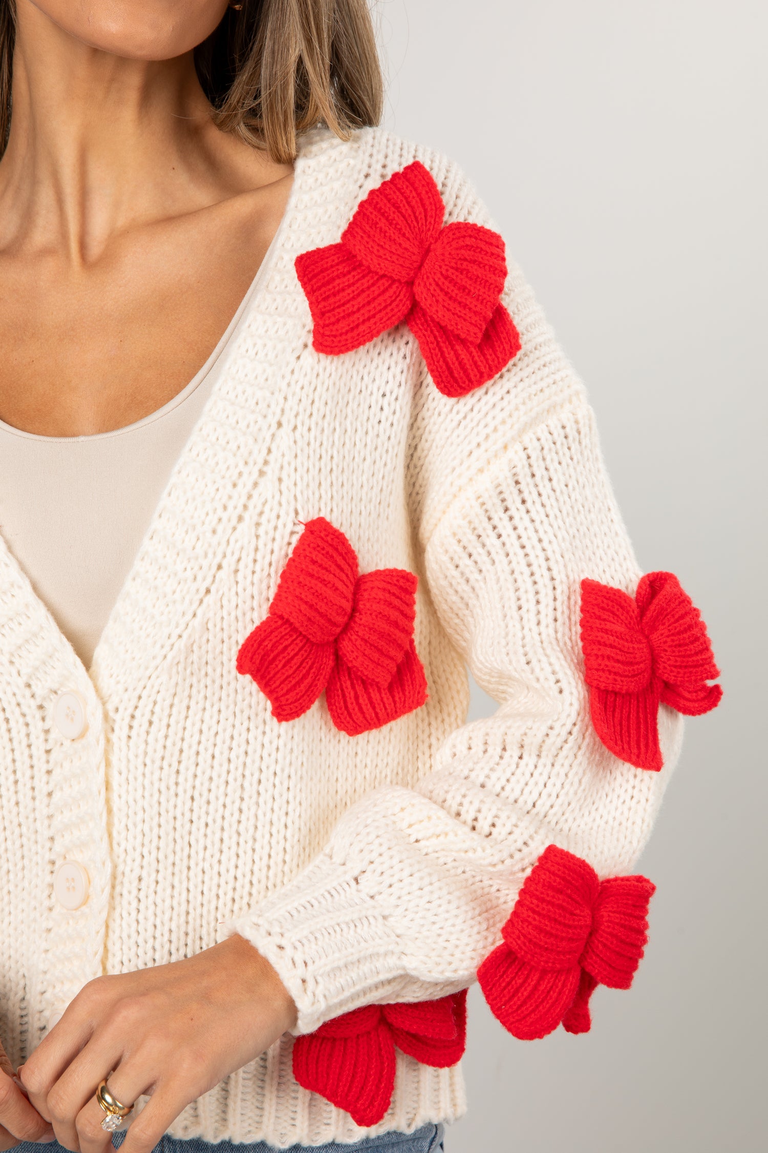 White sweater with red bow designs on a gray background