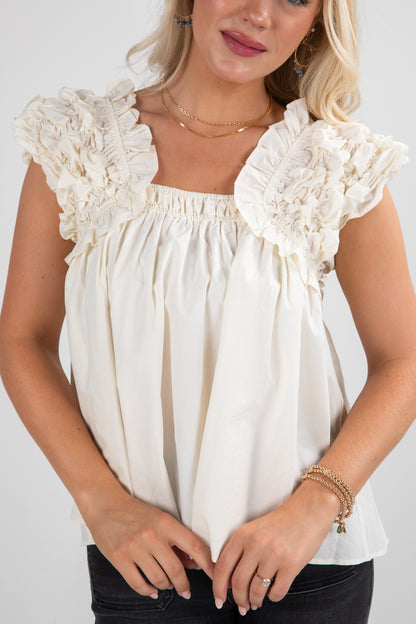 Woman wearing a white blouse with lace details on a plain background