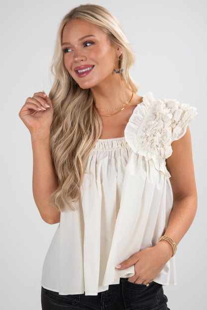 Woman wearing a white blouse with ruffled sleeves against a plain background