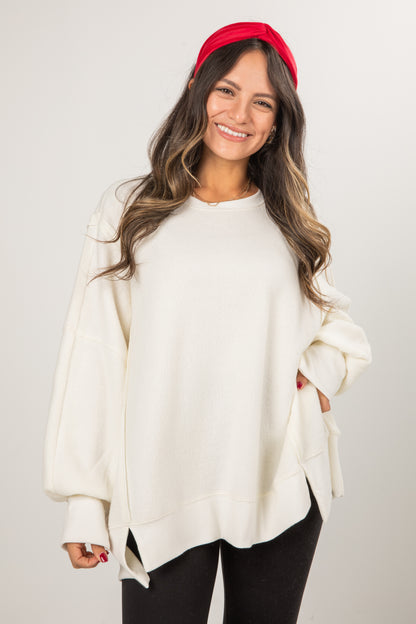 Woman wearing a white sweater and red headband against a plain background