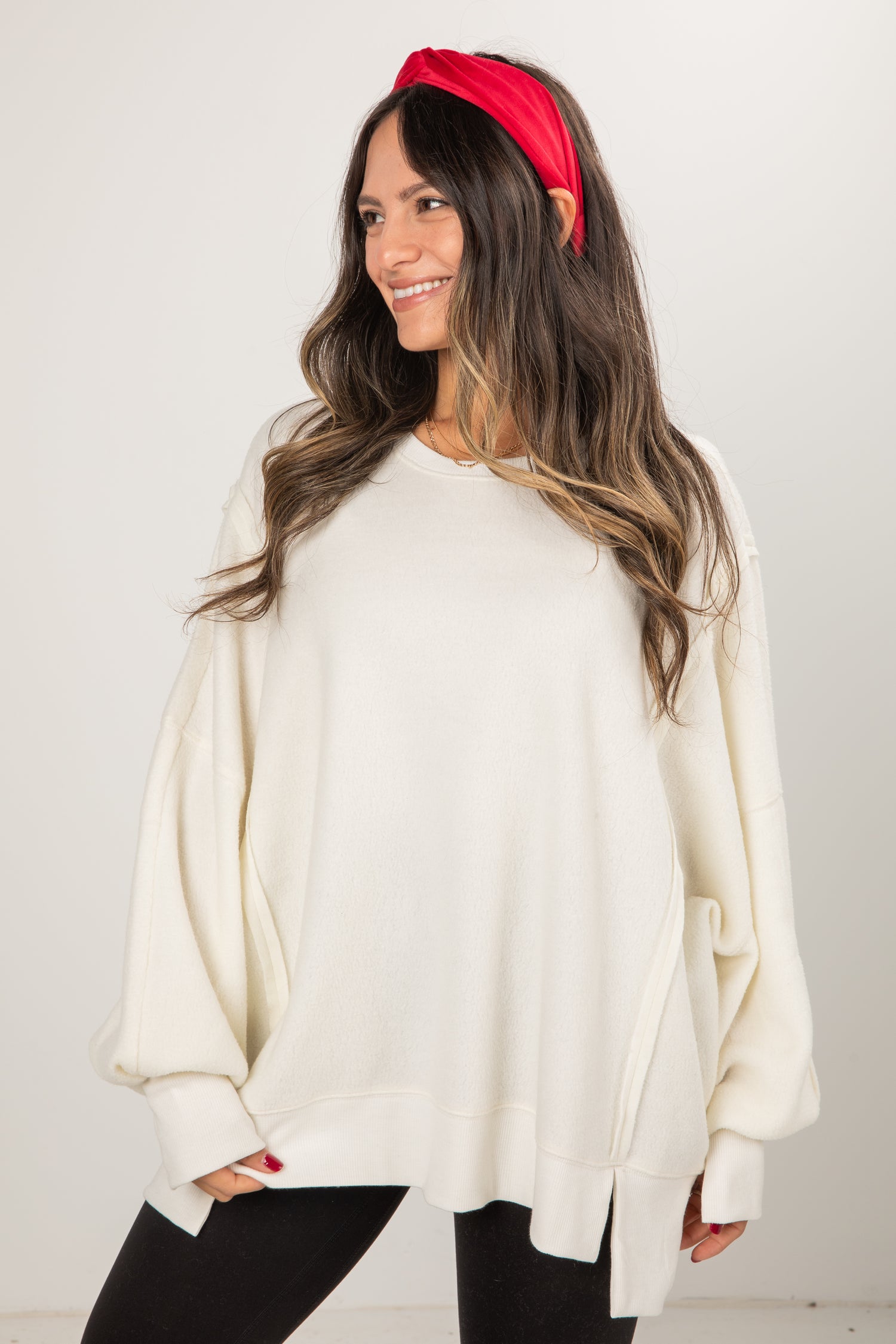 Woman wearing a white sweater and red headband against a plain background