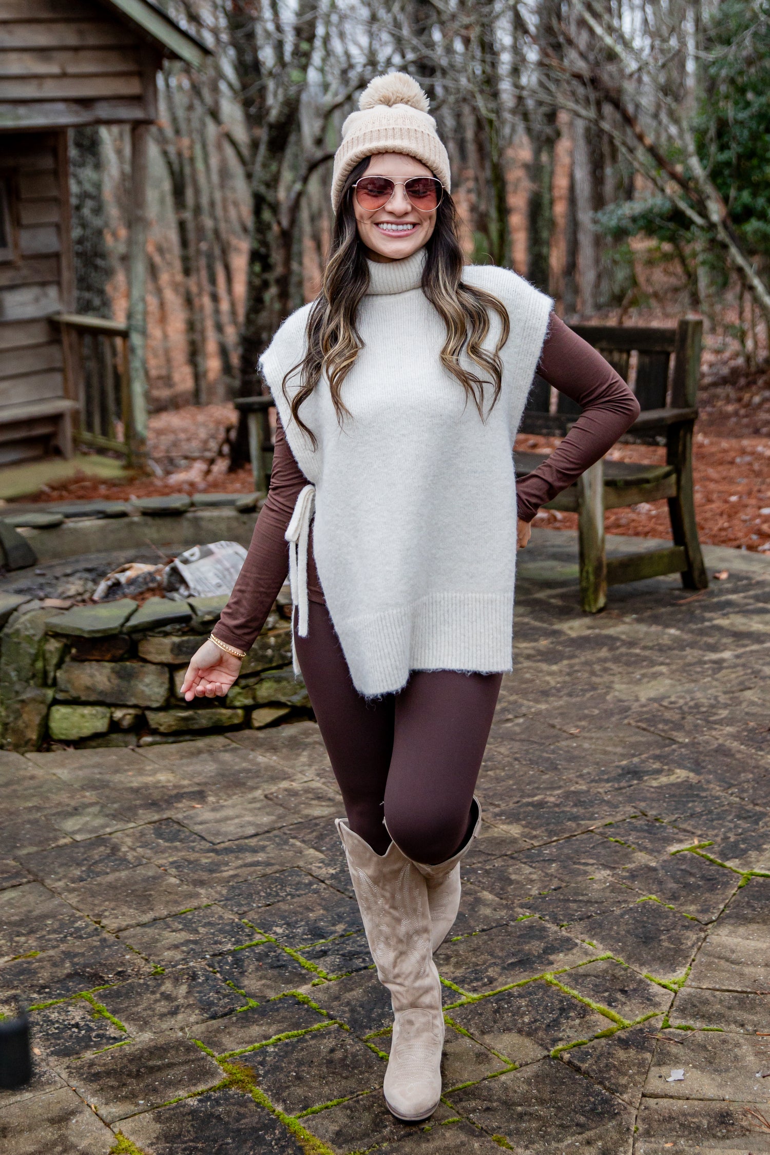 Woman in winter clothing standing outdoors on a stone path with trees in the background