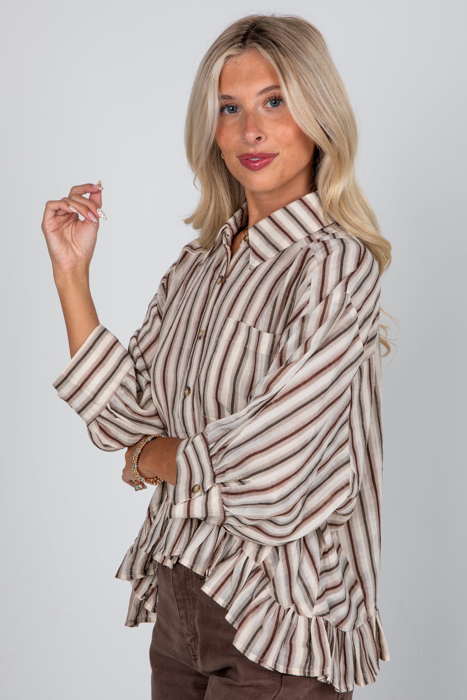 Woman wearing a striped shirt with ruffled details on a plain background