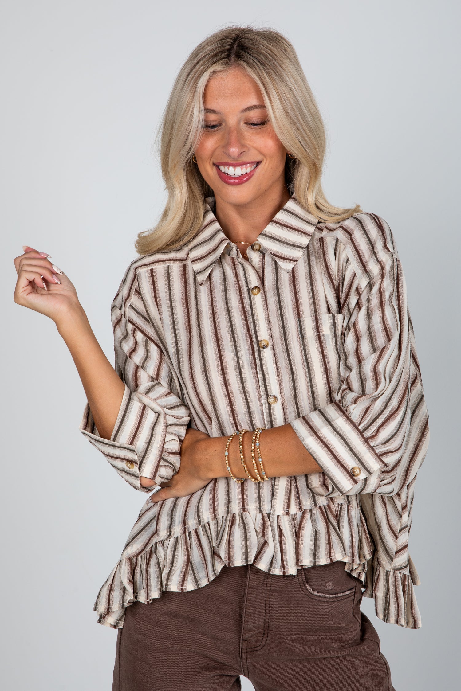 Woman wearing a striped blouse with ruffled details on a plain background