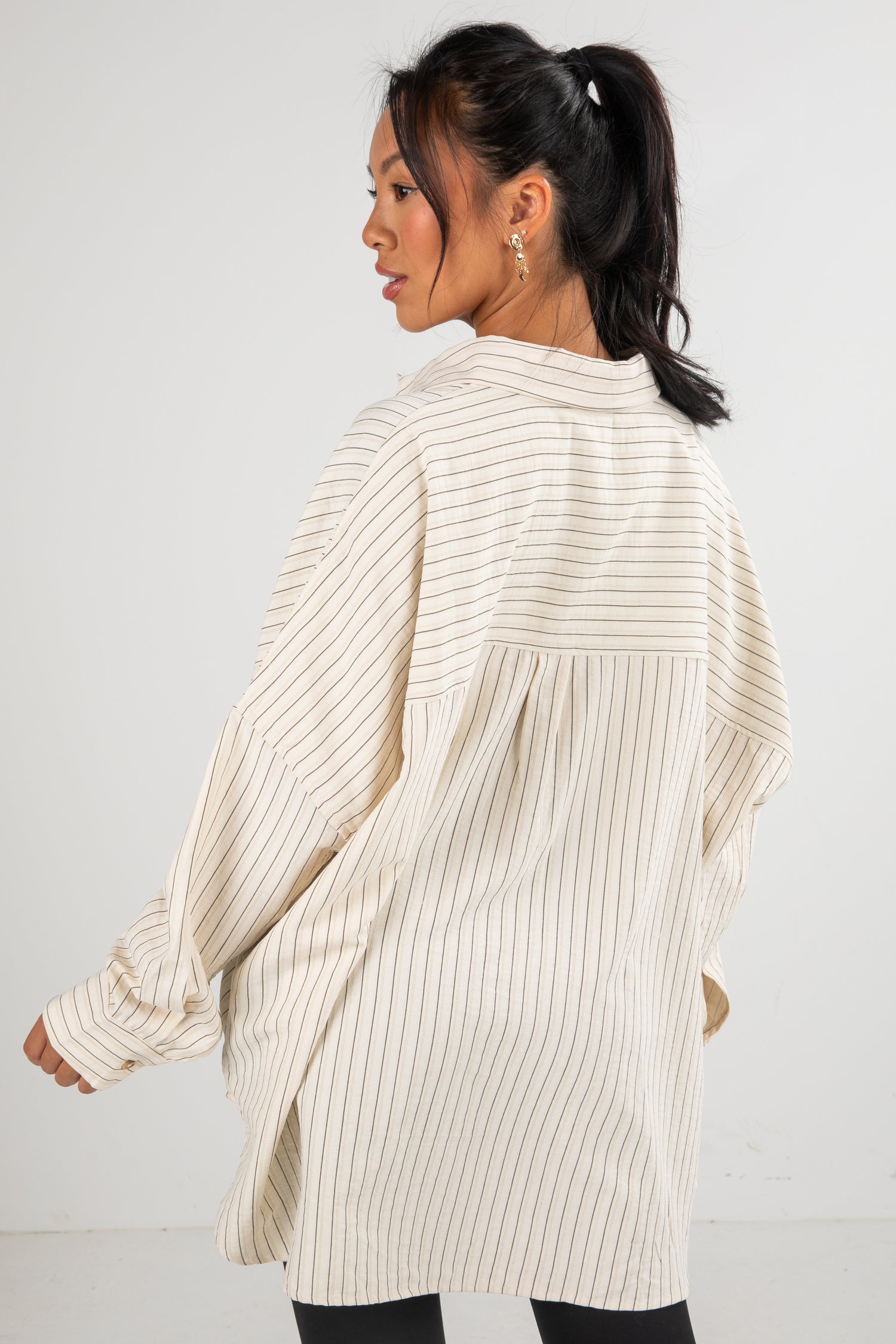 Woman wearing a cream ribbed cardigan against a white background