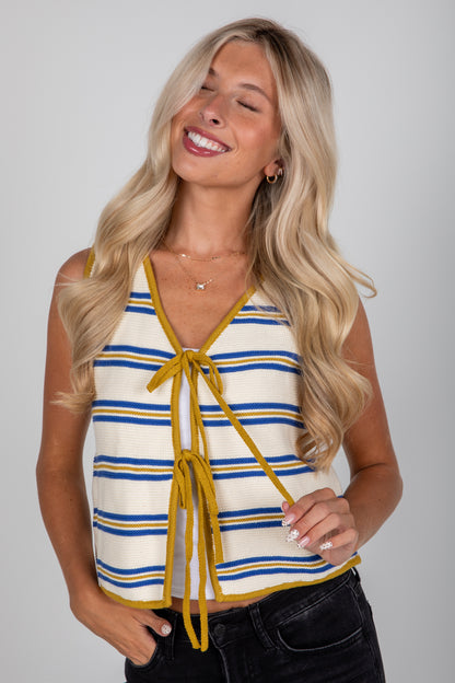 Woman wearing a striped tank top with yellow accents against a plain background