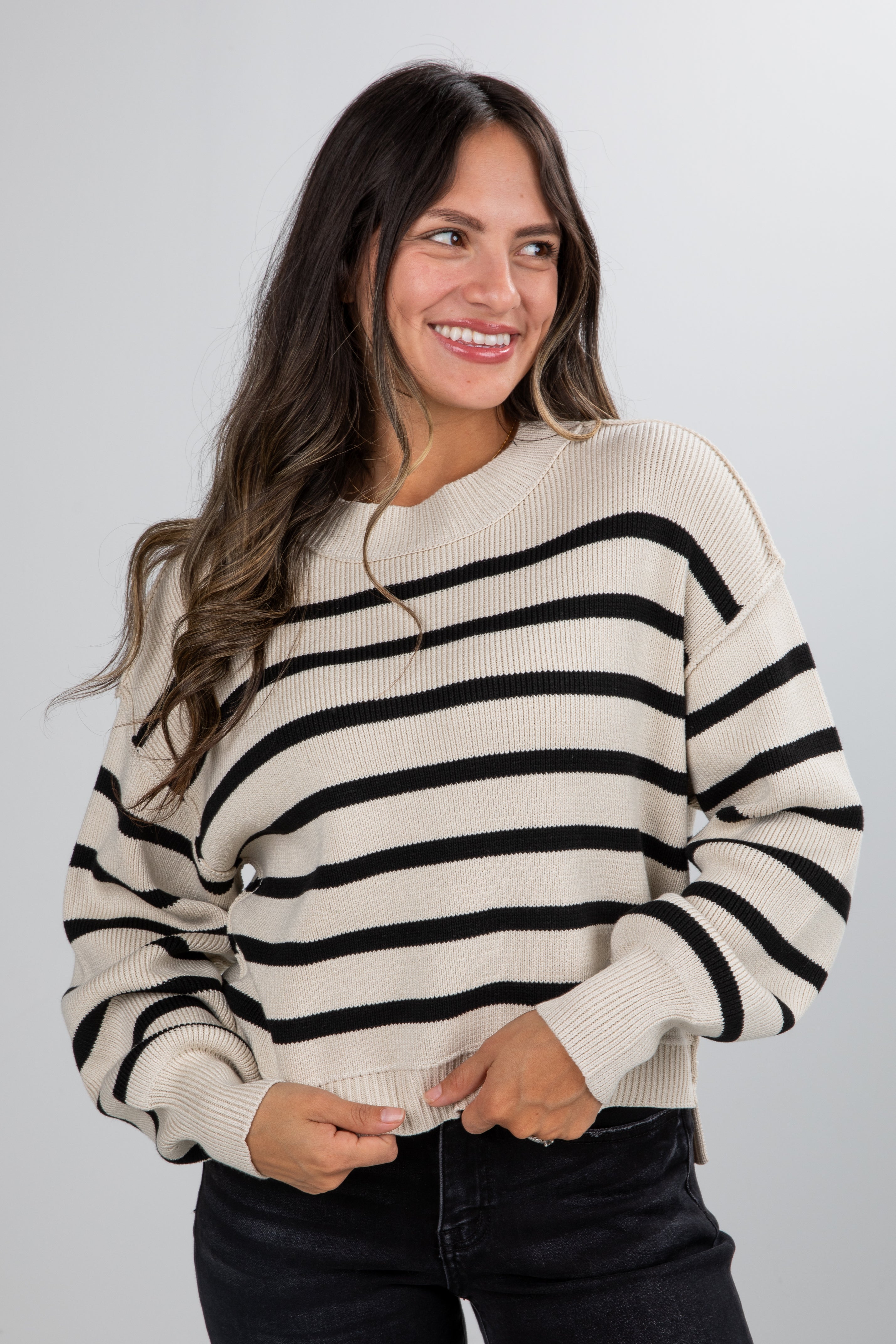 Woman wearing a black and white striped sweater against a plain background