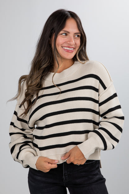 Woman wearing a black and white striped sweater against a plain background