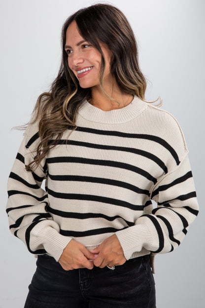 Woman wearing a black and white striped sweater against a plain background