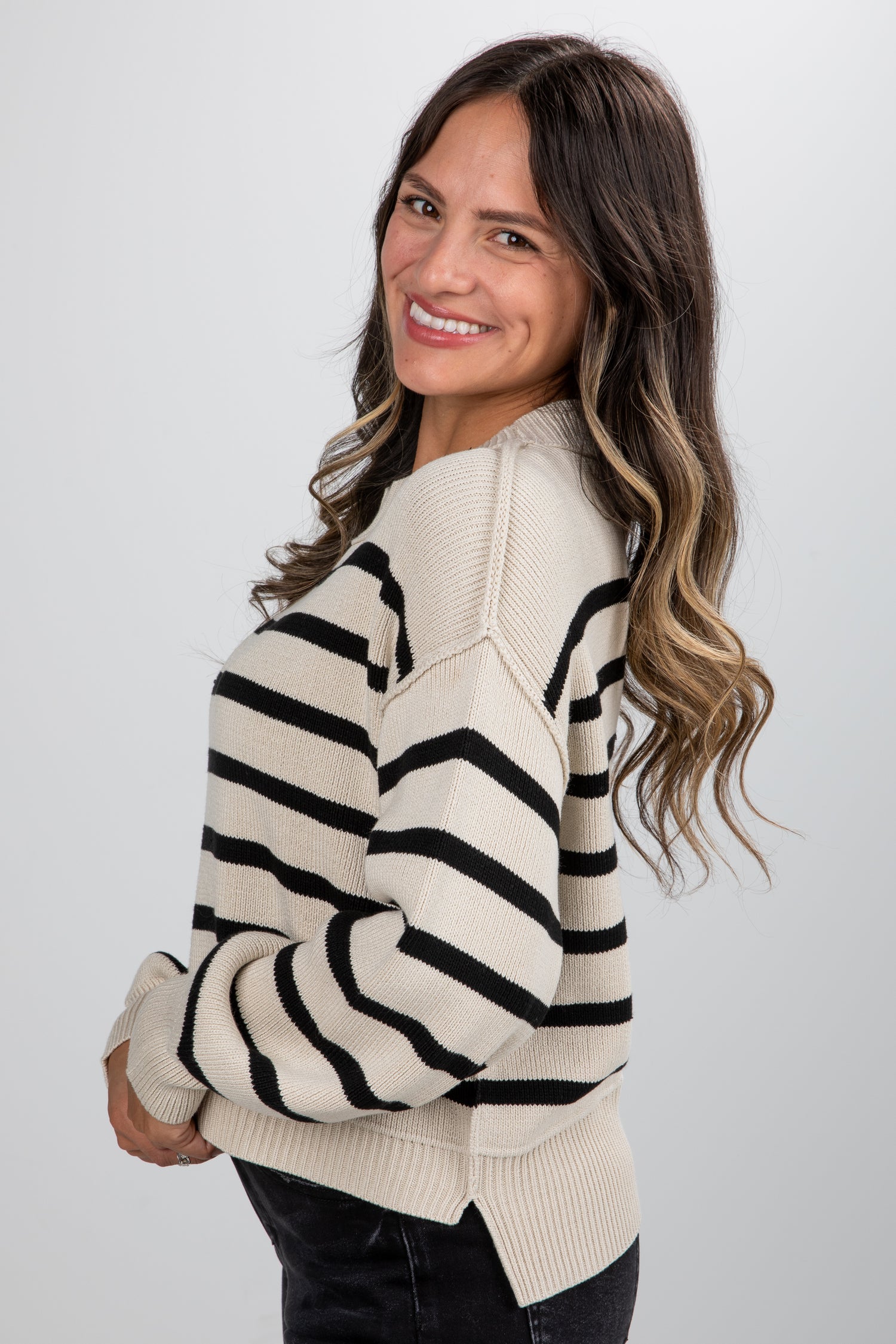 Woman wearing a cream and black striped sweater against a white background