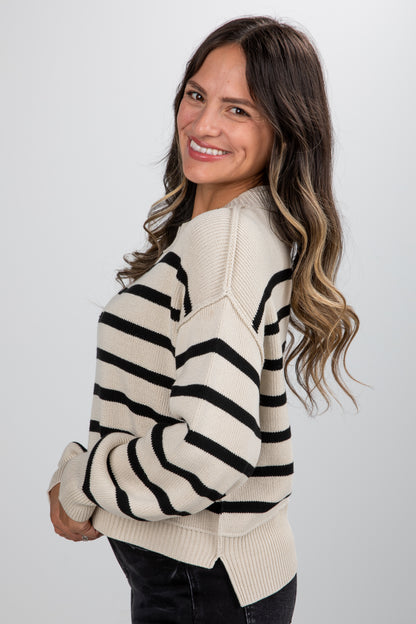 Woman wearing a cream and black striped sweater against a white background