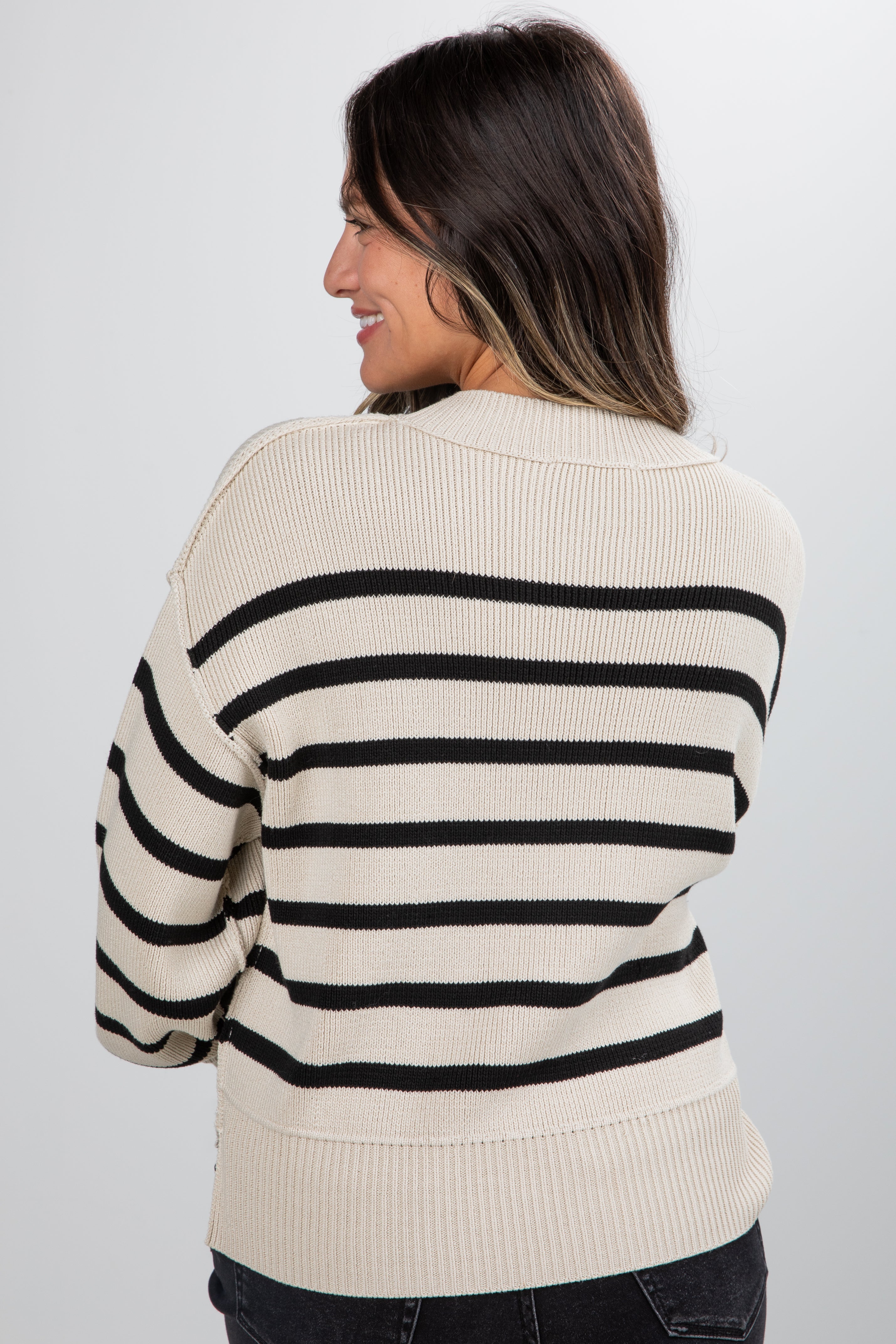 Woman wearing a cream and black striped sweater against a white background