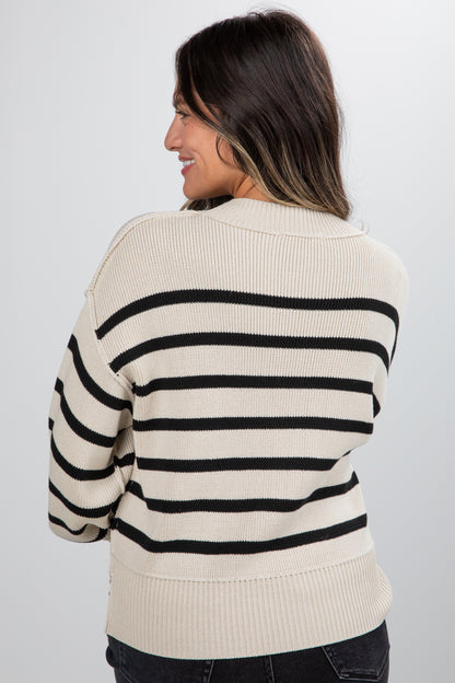 Woman wearing a cream and black striped sweater against a white background