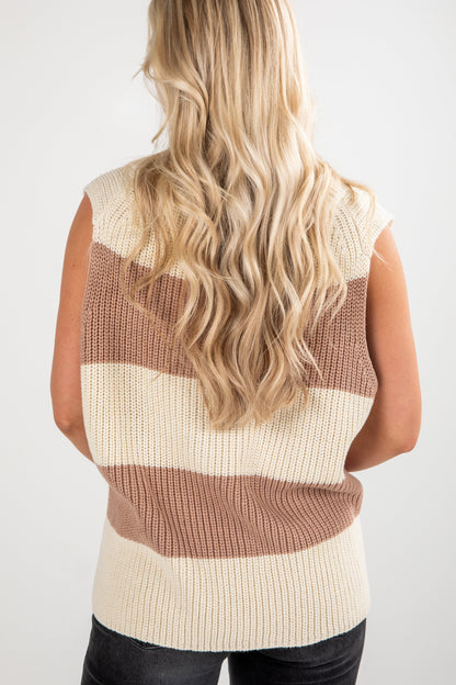 Woman wearing a beige and brown striped sleeveless sweater against a white background