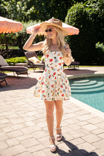 Woman in a patterned dress and sun hat by a poolside