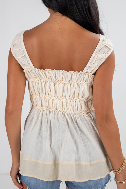 Woman wearing a light-colored top with lace details on a white background