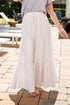 Person wearing a light-colored tiered skirt on a paved outdoor patio.