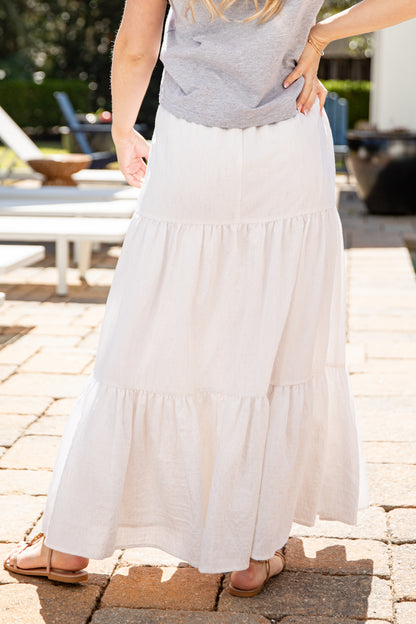 Person wearing a white skirt and gray top on a patio
